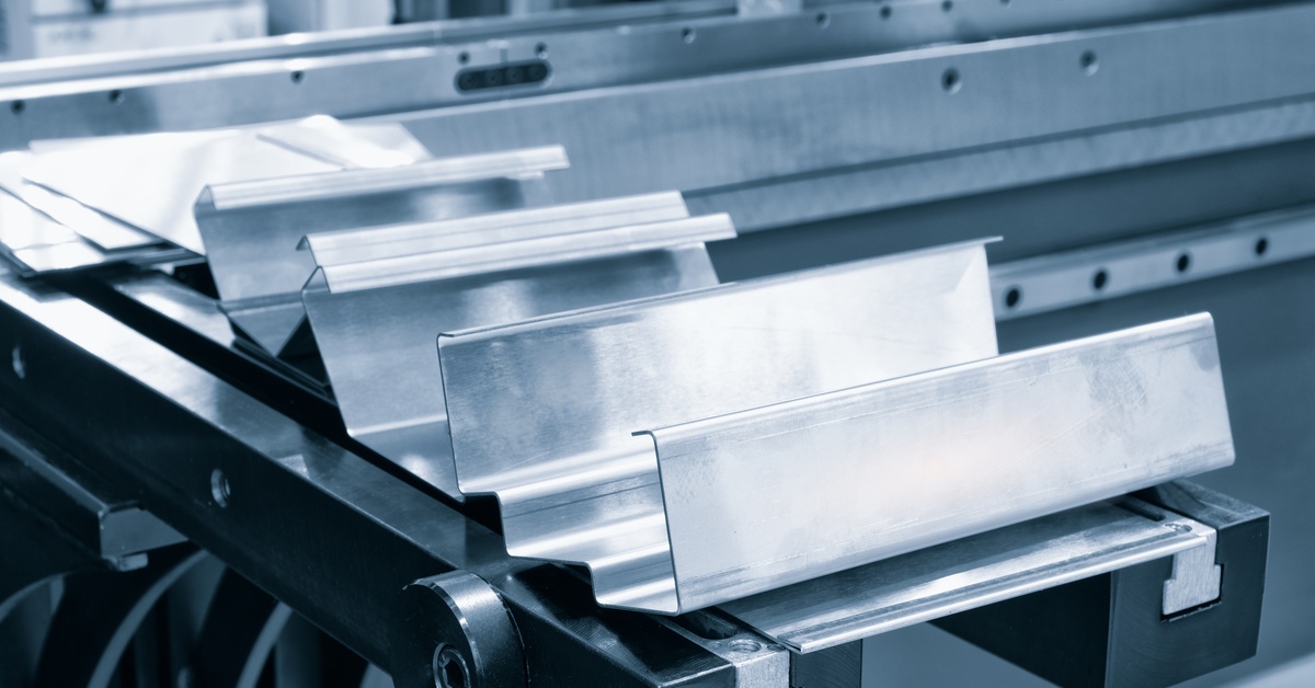 A close-up view of a shiny piece of metal on an industrial machine showcases its precise U-shaped bends.