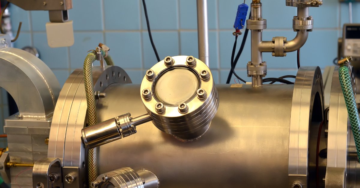 A stainless steel vacuum chamber uses valves, gauges, and sensors for a controlled finishing process.
